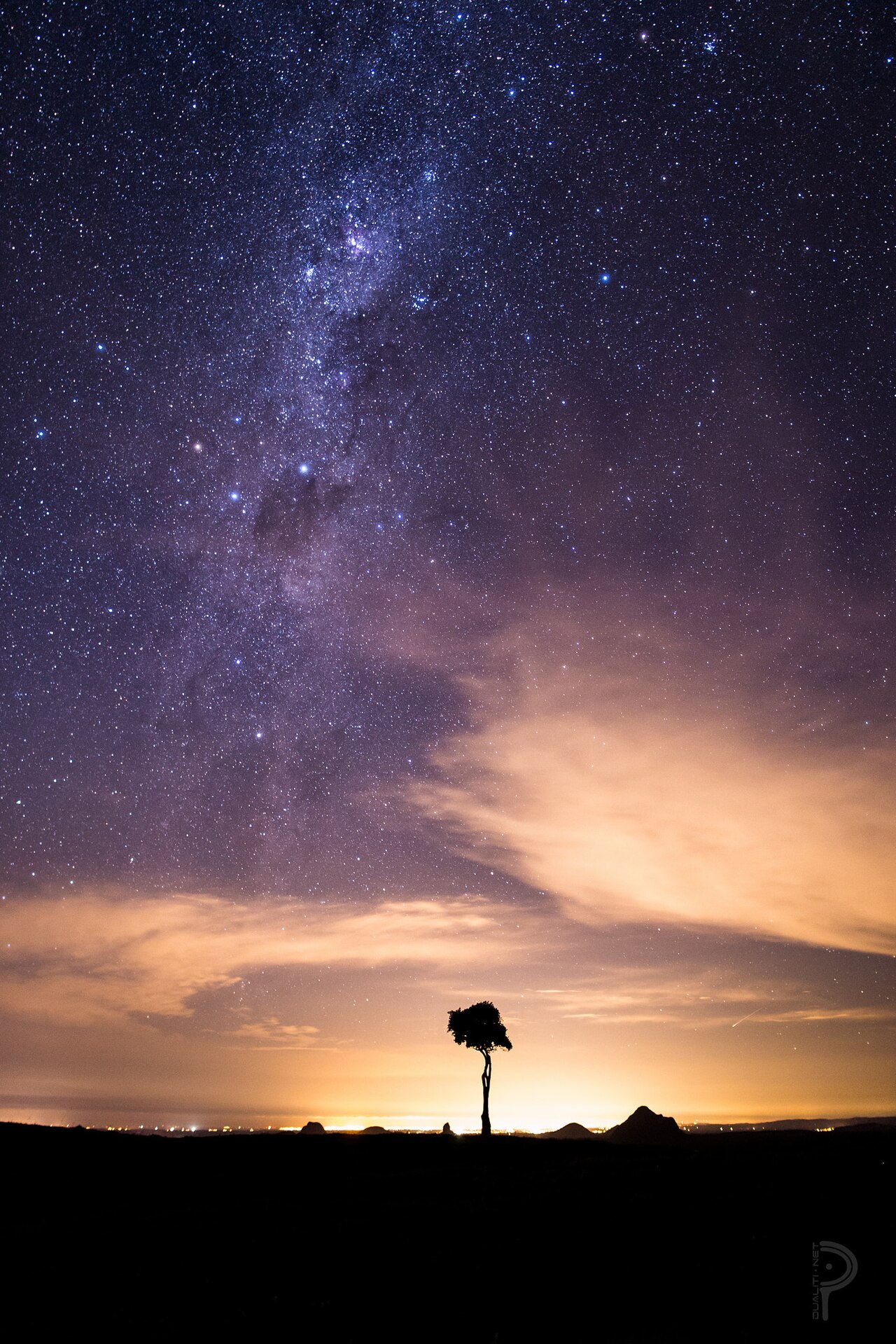 The Milky Way above One Tree Hill at night, with the Glass House Mountains and coastal lights below